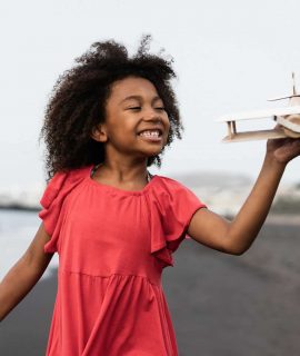 african-kid-running-on-the-beach-while-playing-with-wood-toy-airplane-focus-on-face.jpg